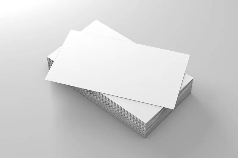 A stack of blank white business cards neatly arranged on a sleek grey surface.