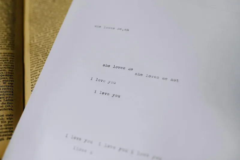 A close-up of typewritten text expressing love on white paper with an old book in the background.